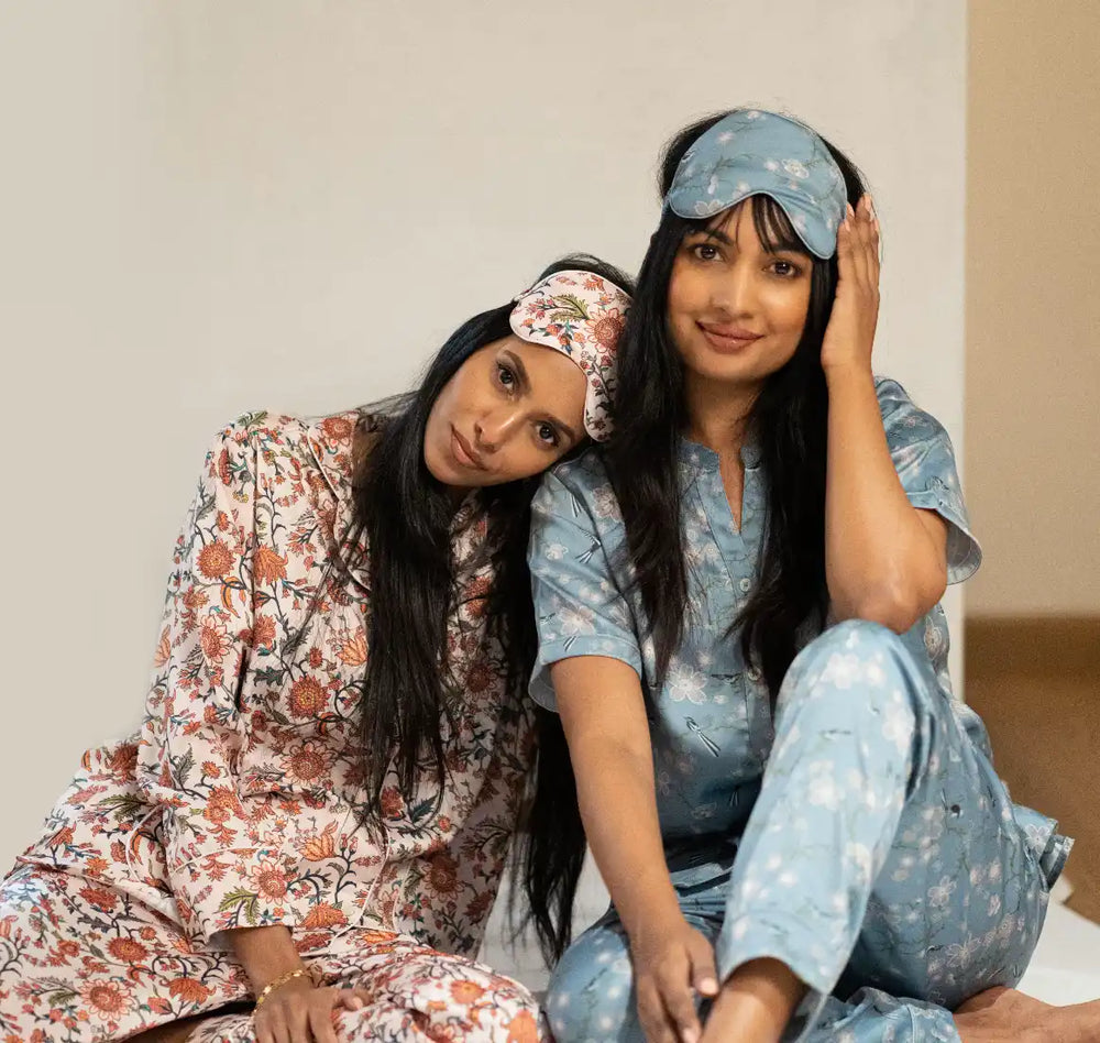 Two women in matching floral pajamas and eye masks.
