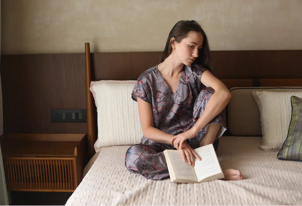 A woman in patterned pajamas holding an open book.